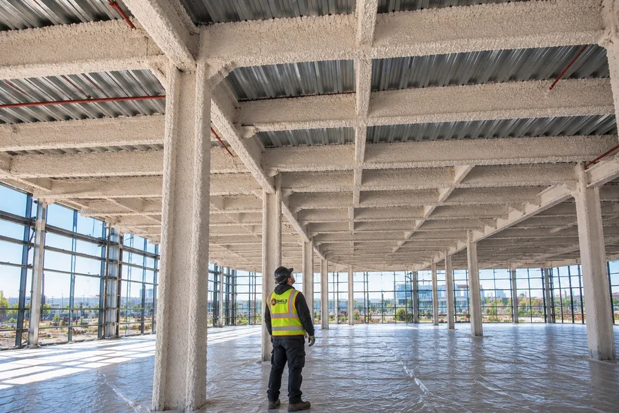 A Shield crew member in a high-visibility vest inside an open building under construction.